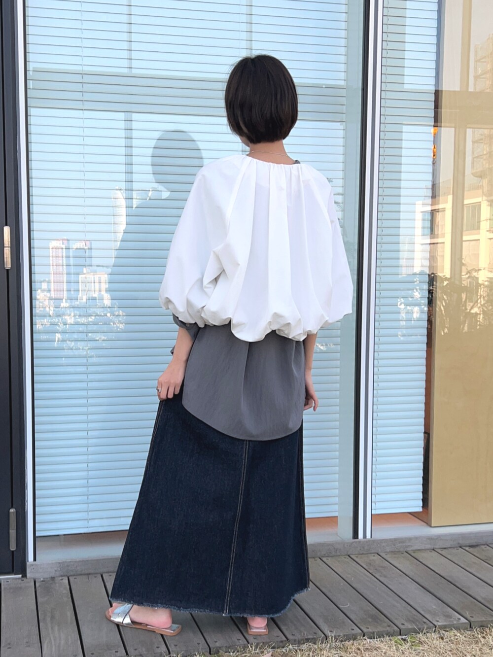 ブルー系のデニムスカート、ホワイト系のブルゾン、グレー系のシャツ/ブラウスを着用したレディースの春コーディネートの5枚目の写真