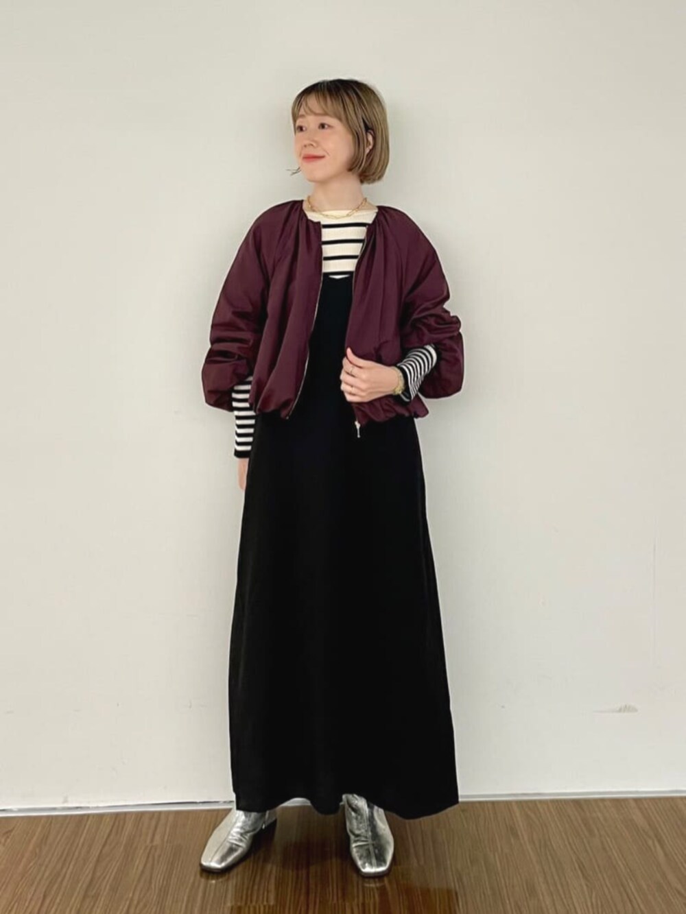 レッド系のブルゾン、ブラック系のワンピース、ベージュ系のニット/セーターを着用したレディースの秋コーディネートの2枚目の写真