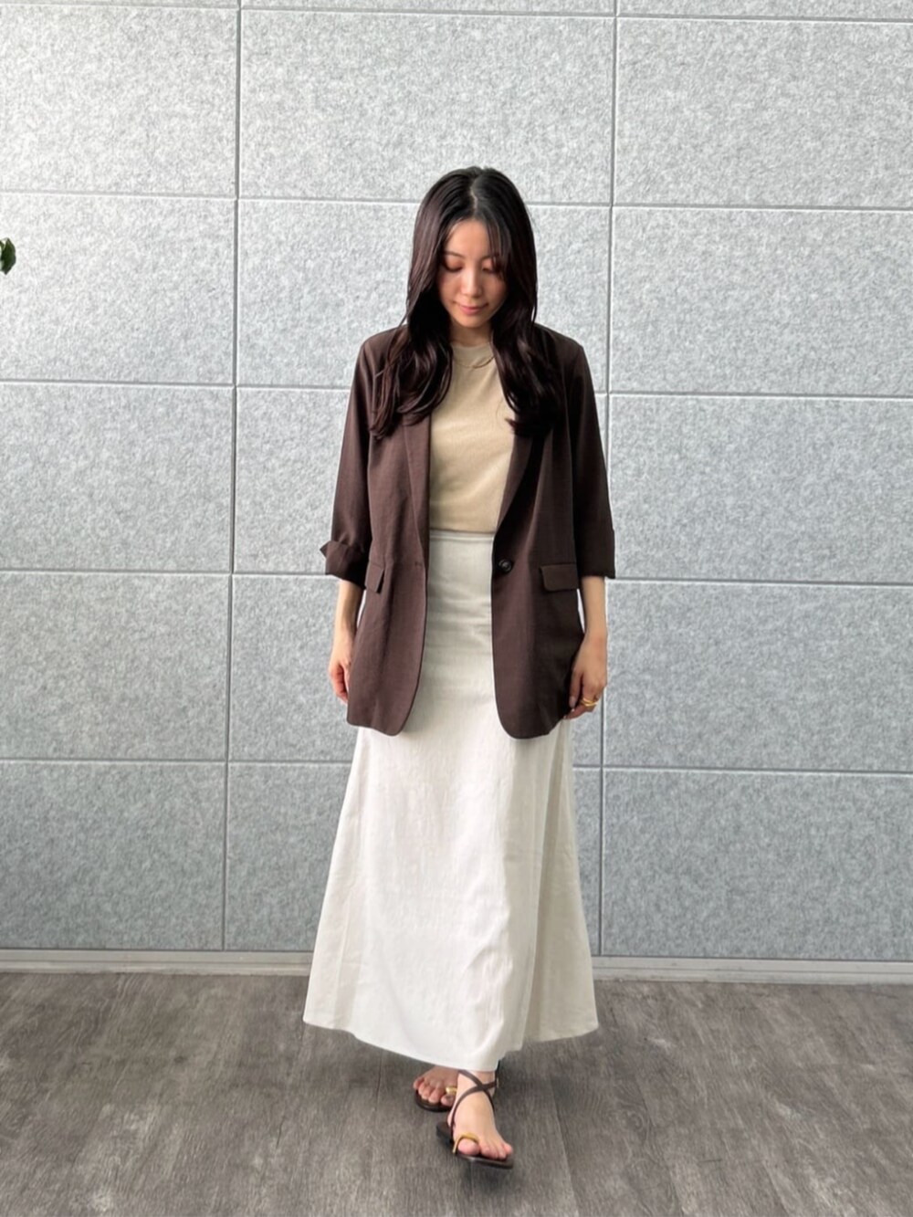 ホワイト系のスカート、ベージュ系のTシャツ/カットソー、ブラウン系のテーラードジャケットを着用したレディースの夏コーディネートの3枚目の写真