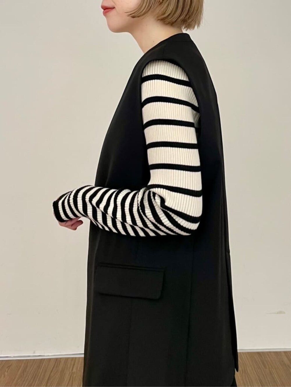 ブラック系のワンピース、ベージュ系のニット/セーター、ブラック系のベストを着用したレディースの秋コーディネートの6枚目の写真