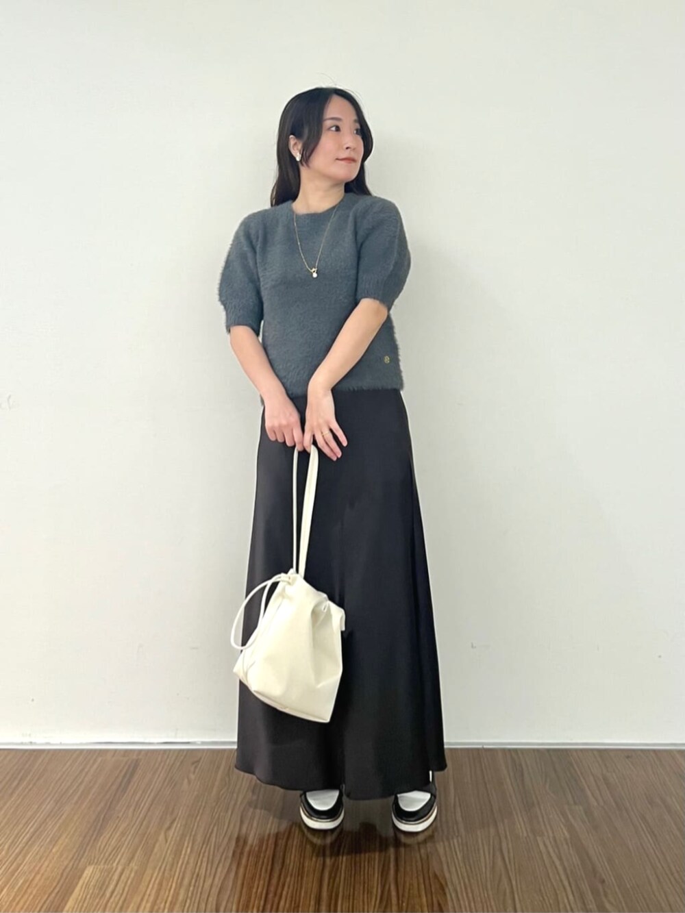 グレー系のニット/セーター、グレー系のスカートを着用したレディースの秋コーディネートの2枚目の写真