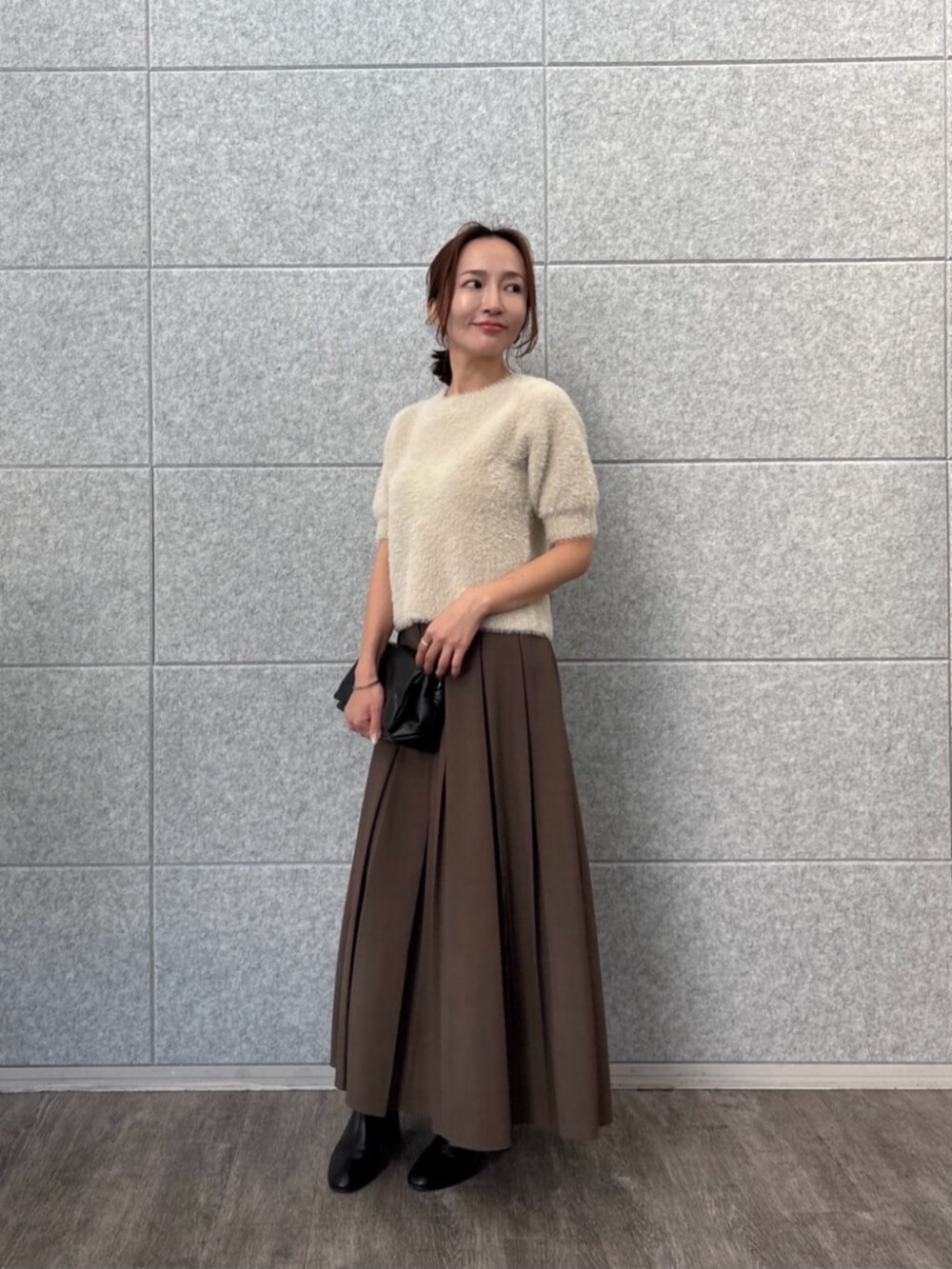 ベージュ系のニット/セーター、ブラウン系のスカートを着用したレディースの秋コーディネートの3枚目の写真