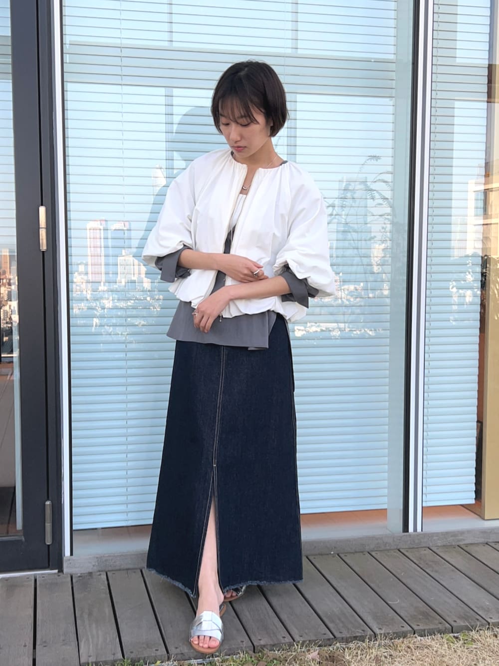 ブルー系のデニムスカート、ホワイト系のブルゾン、グレー系のシャツ/ブラウスを着用したレディースの春コーディネートの3枚目の写真