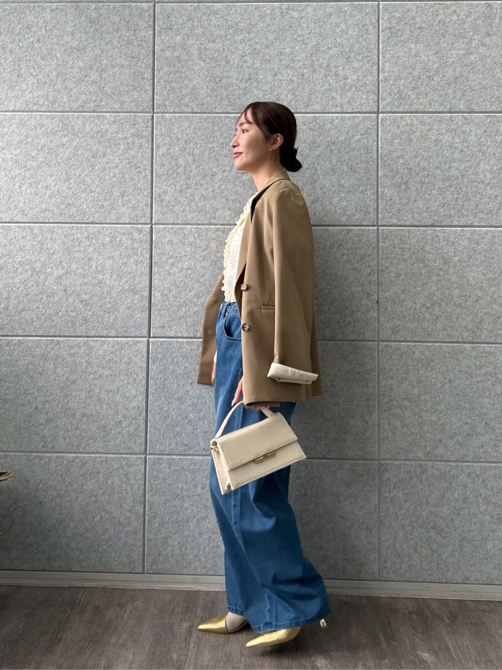 イエロー系のテーラードジャケット、ホワイト系のシャツ/ブラウス、ブルー系のデニムパンツを着用したレディースの冬コーディネートの3枚目の写真