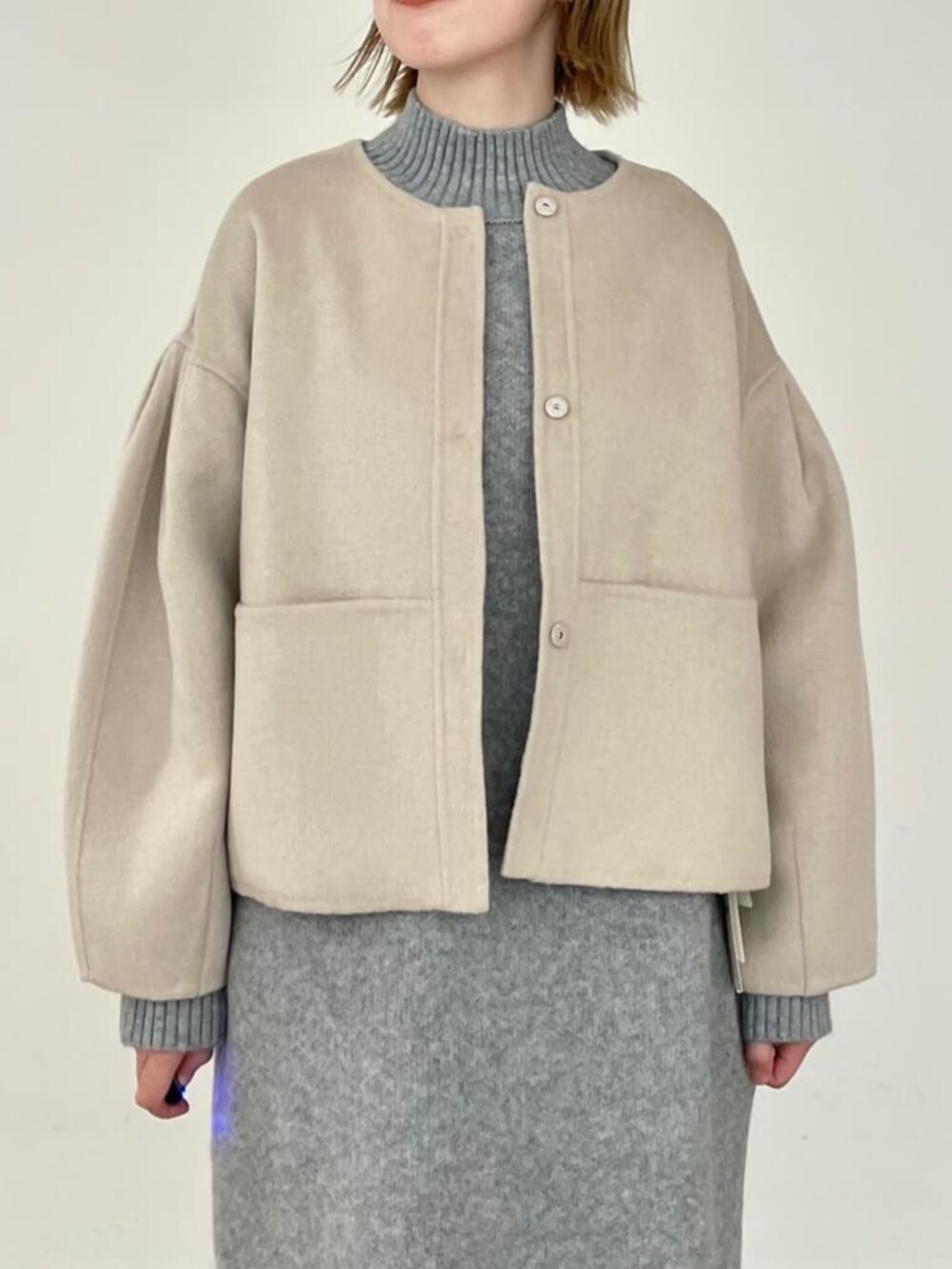 グレー系のワンピース、ベージュ系のノーカラーコートを着用したレディースの秋コーディネートの5枚目の写真