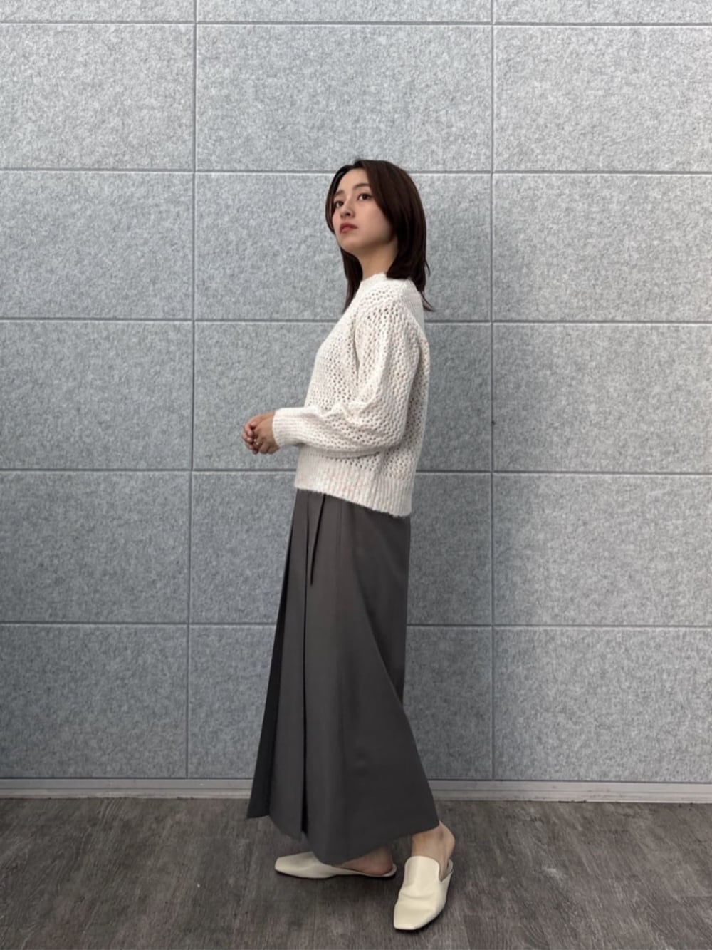 グレー系のスカート、ホワイト系のニット/セーターを着用したレディースの秋コーディネートの6枚目の写真