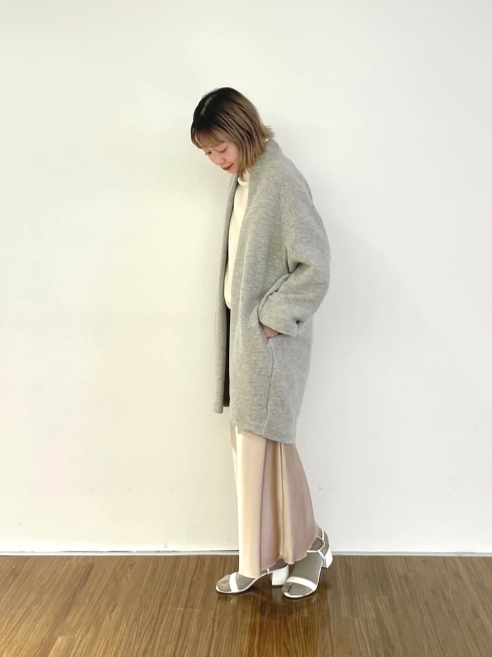 ベージュ系のスカート、ベージュ系のノーカラーコート、ホワイト系のニット/セーターを着用したレディースの秋コーディネートの3枚目の写真