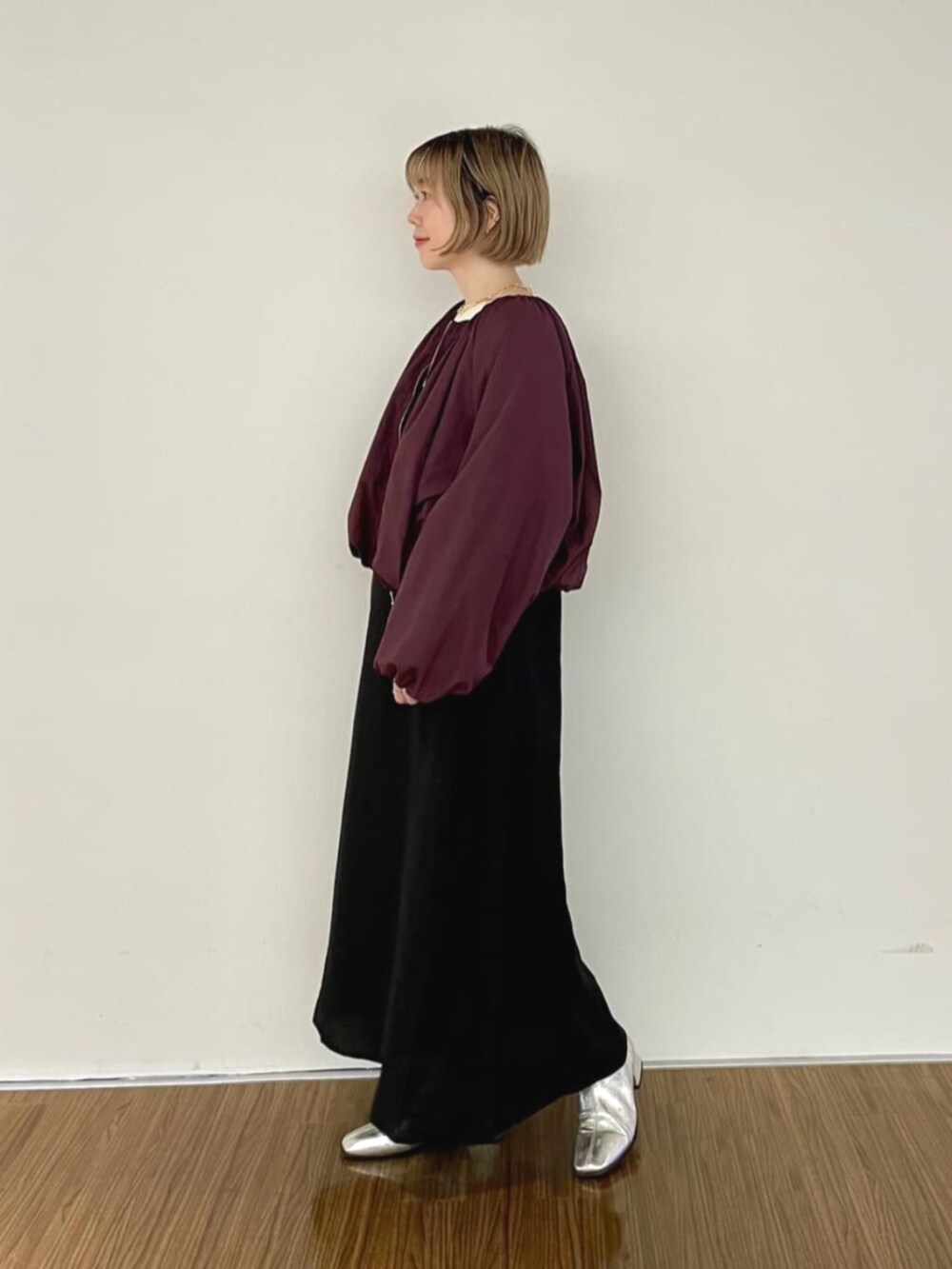 レッド系のブルゾン、ブラック系のワンピース、ベージュ系のニット/セーターを着用したレディースの秋コーディネートの5枚目の写真