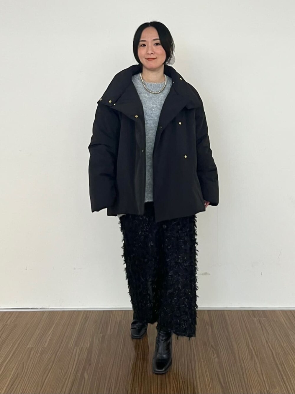 ブラック系のスカート、ブラック系のその他アウター、グレー系のニット/セーターを着用したレディースの冬コーディネートの2枚目の写真