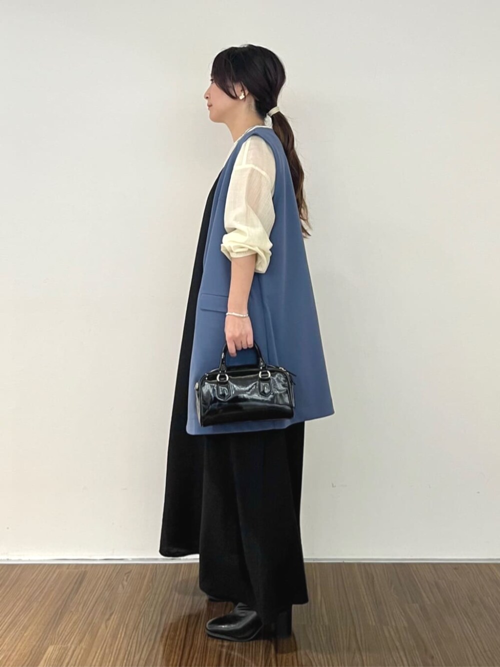 ブラック系のワンピース、ブルー系のベスト、ホワイト系のシャツ/ブラウスを着用したレディースの秋コーディネートの4枚目の写真