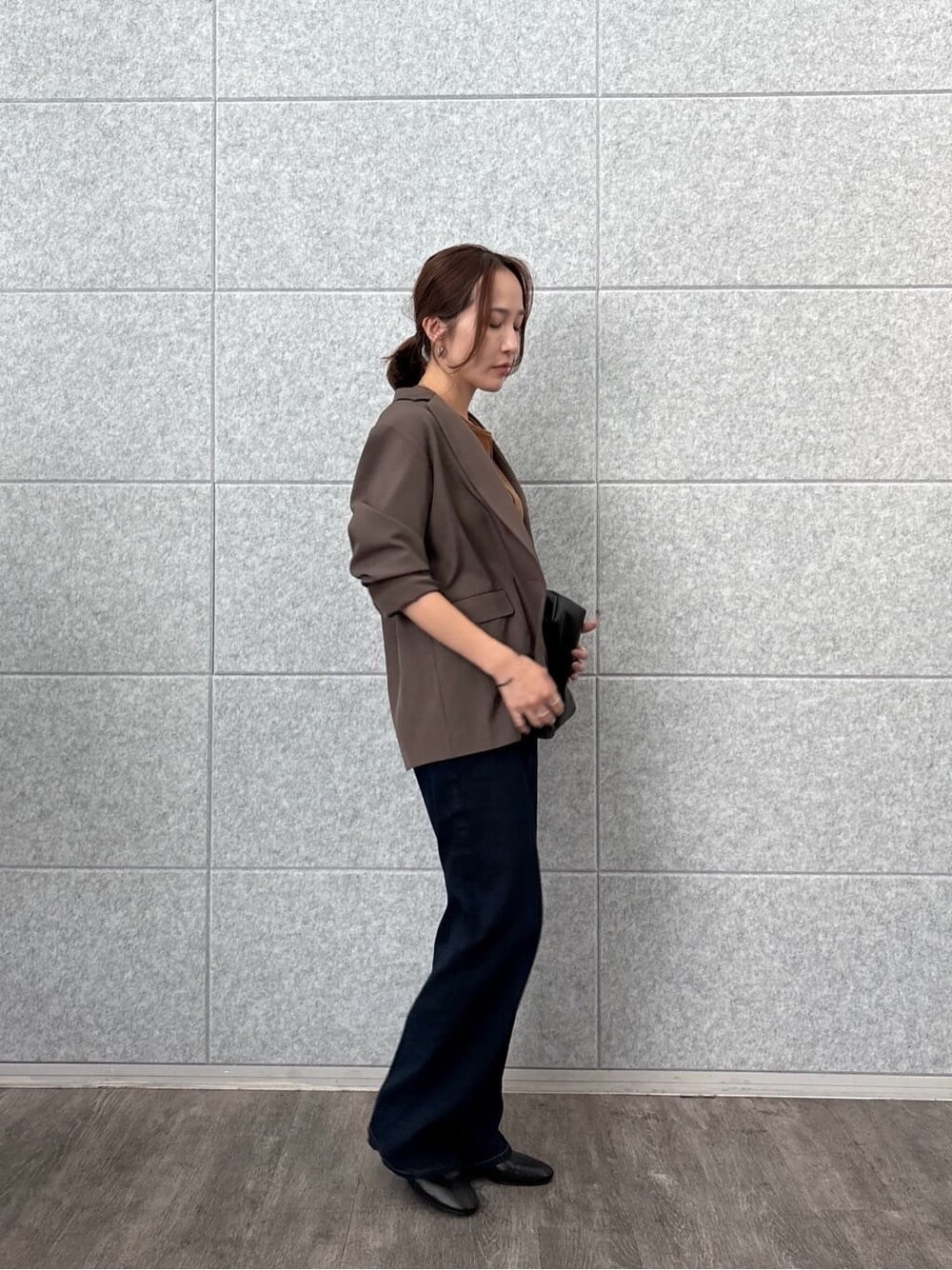 ブラウン系のテーラードジャケット、イエロー系のTシャツ/カットソー、ブルー系のデニムパンツを着用したレディースの秋コーディネートの2枚目の写真