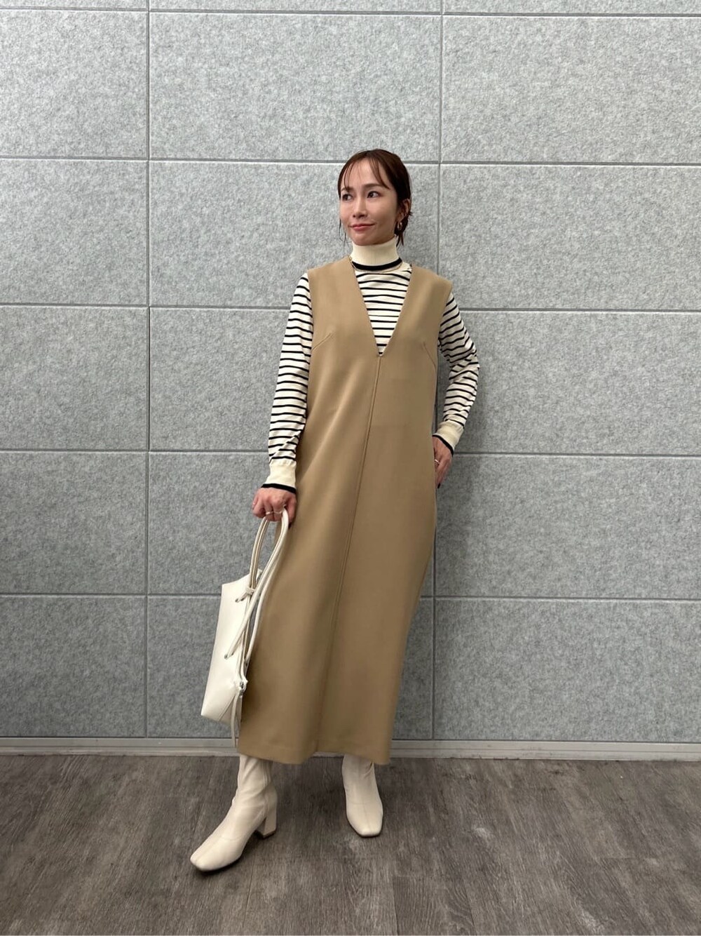 ベージュ系のワンピース、ホワイト系のニット/セーターを着用したレディースの冬コーディネートの2枚目の写真
