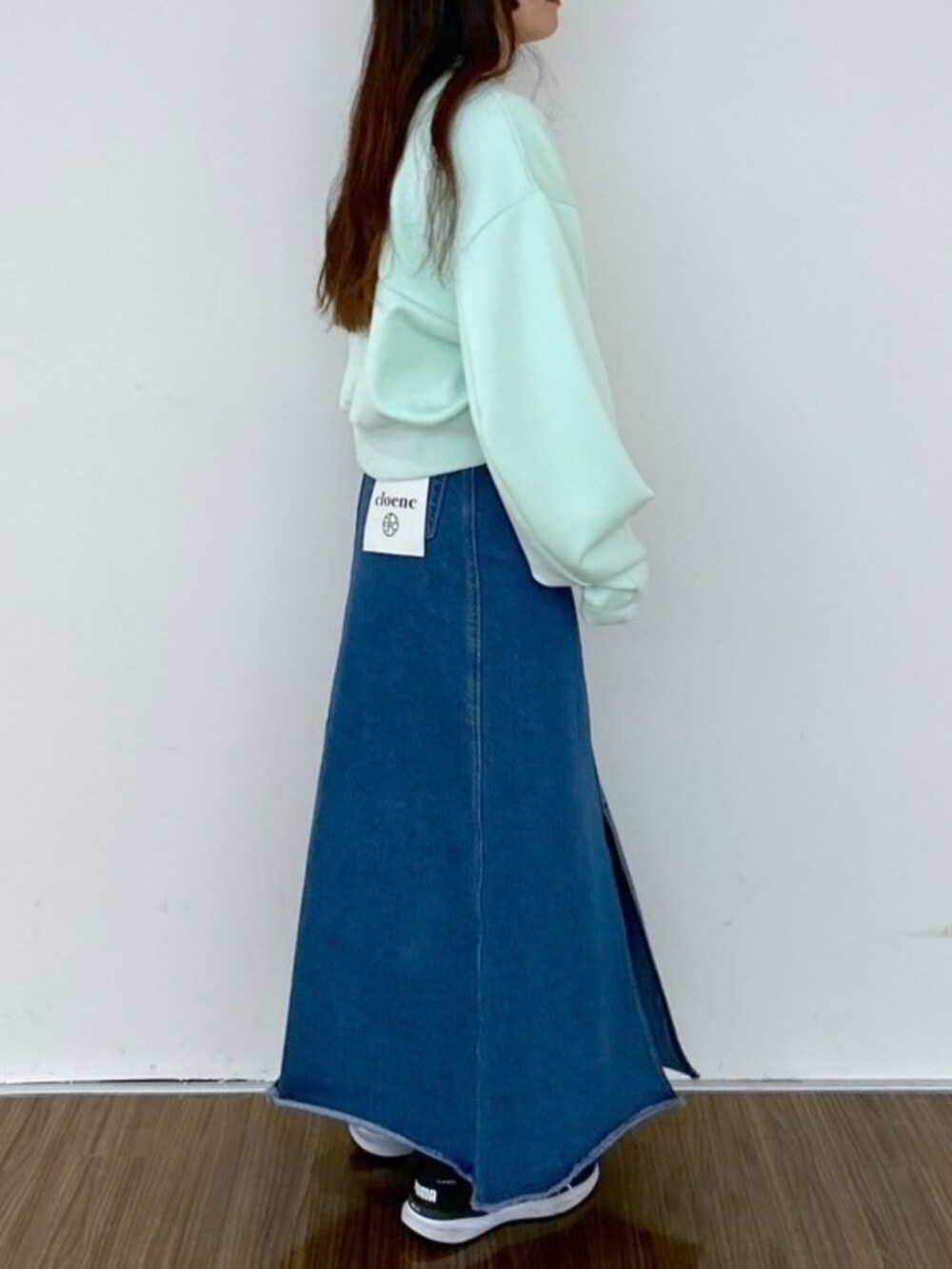 ブルー系のデニムスカート、グリーン系のスウェットを着用したレディースの春コーディネートの4枚目の写真