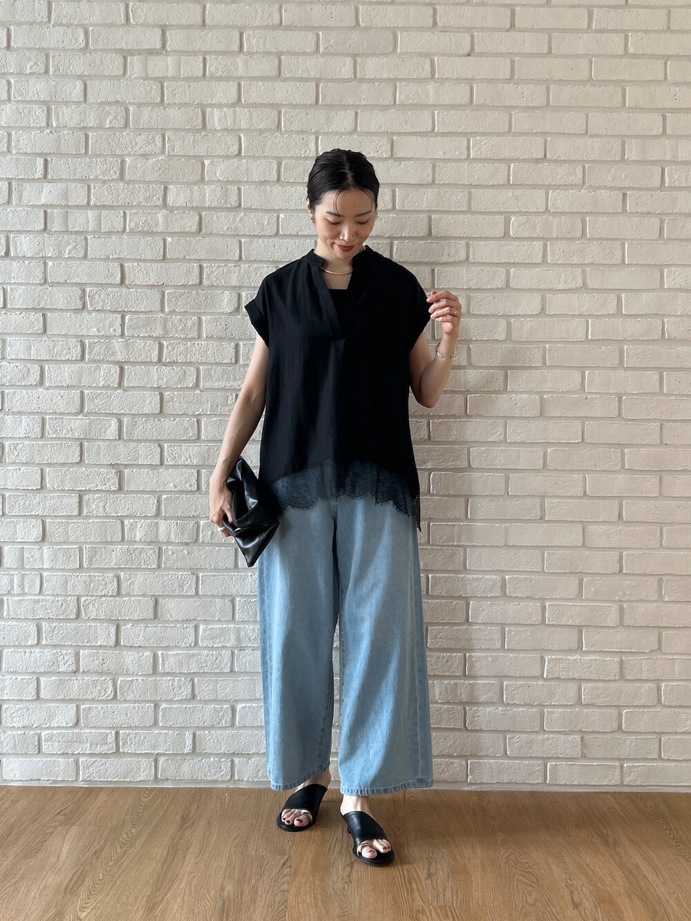 ブラック系のシャツ/ブラウス、ブルー系のデニムパンツを着用したレディースの春コーディネートの2枚目の写真