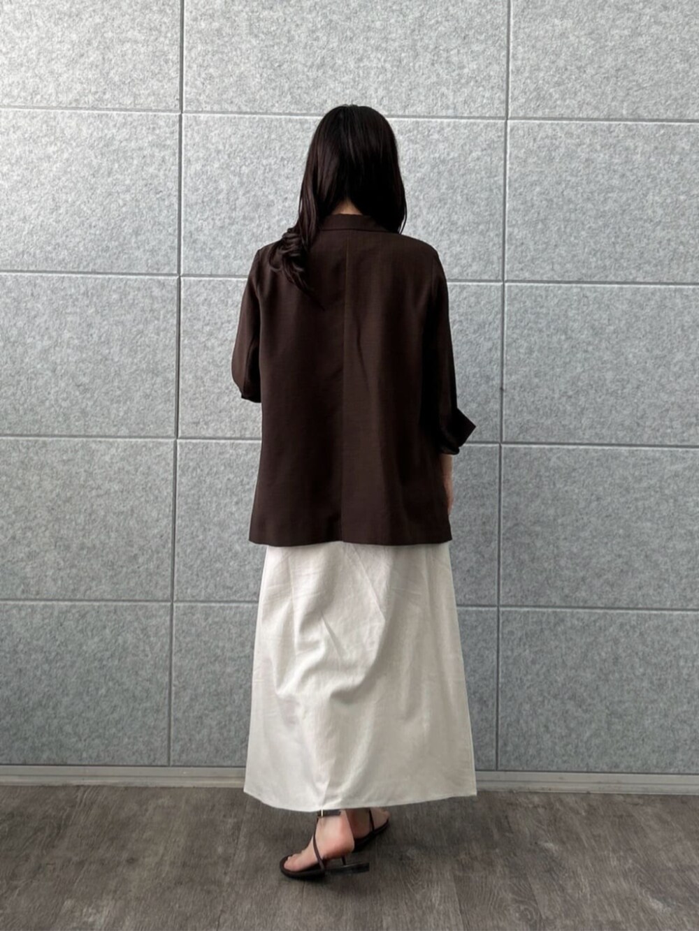 ホワイト系のスカート、ベージュ系のTシャツ/カットソー、ブラウン系のテーラードジャケットを着用したレディースの夏コーディネートの2枚目の写真