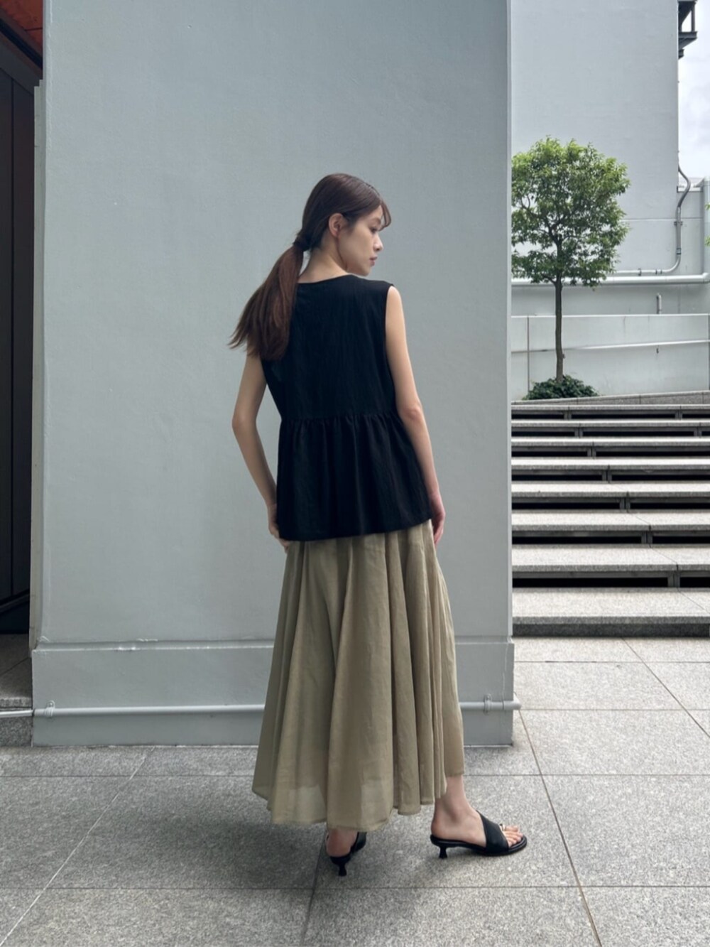 グリーン系のスカート、ブラック系のタンクトップ、ブラック系のシャツ/ブラウスを着用したレディースの夏コーディネートの3枚目の写真