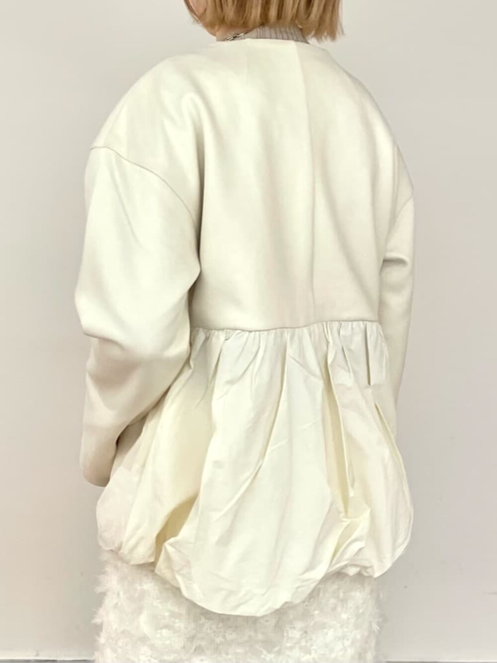 ホワイト系のスカート、ゴールド系のニット/セーター、ホワイト系のブルゾンを着用したレディースの冬コーディネートの6枚目の写真