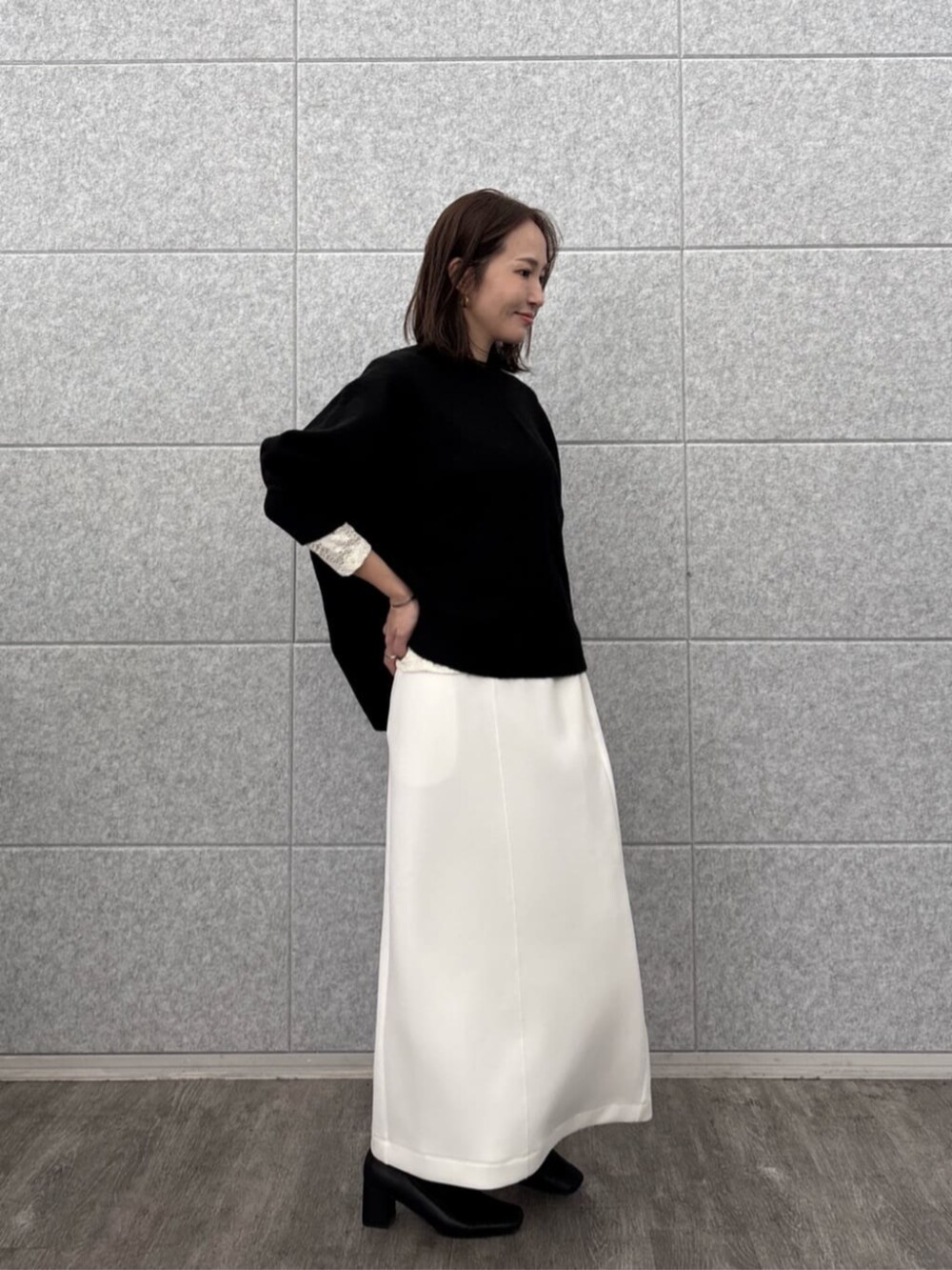 ホワイト系のスカート、ホワイト系のTシャツ/カットソー、ブラック系のニット/セーターを着用したレディースの秋コーディネートの3枚目の写真