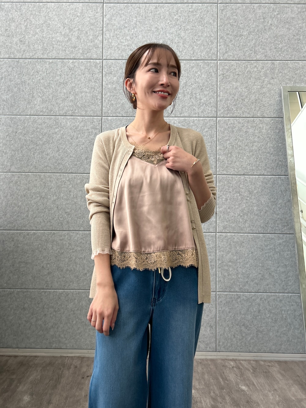 ベージュ系のカーディガン/ボレロ、ベージュ系のタンクトップ、ブルー系のデニムパンツを着用したレディースの秋コーディネートの6枚目の写真
