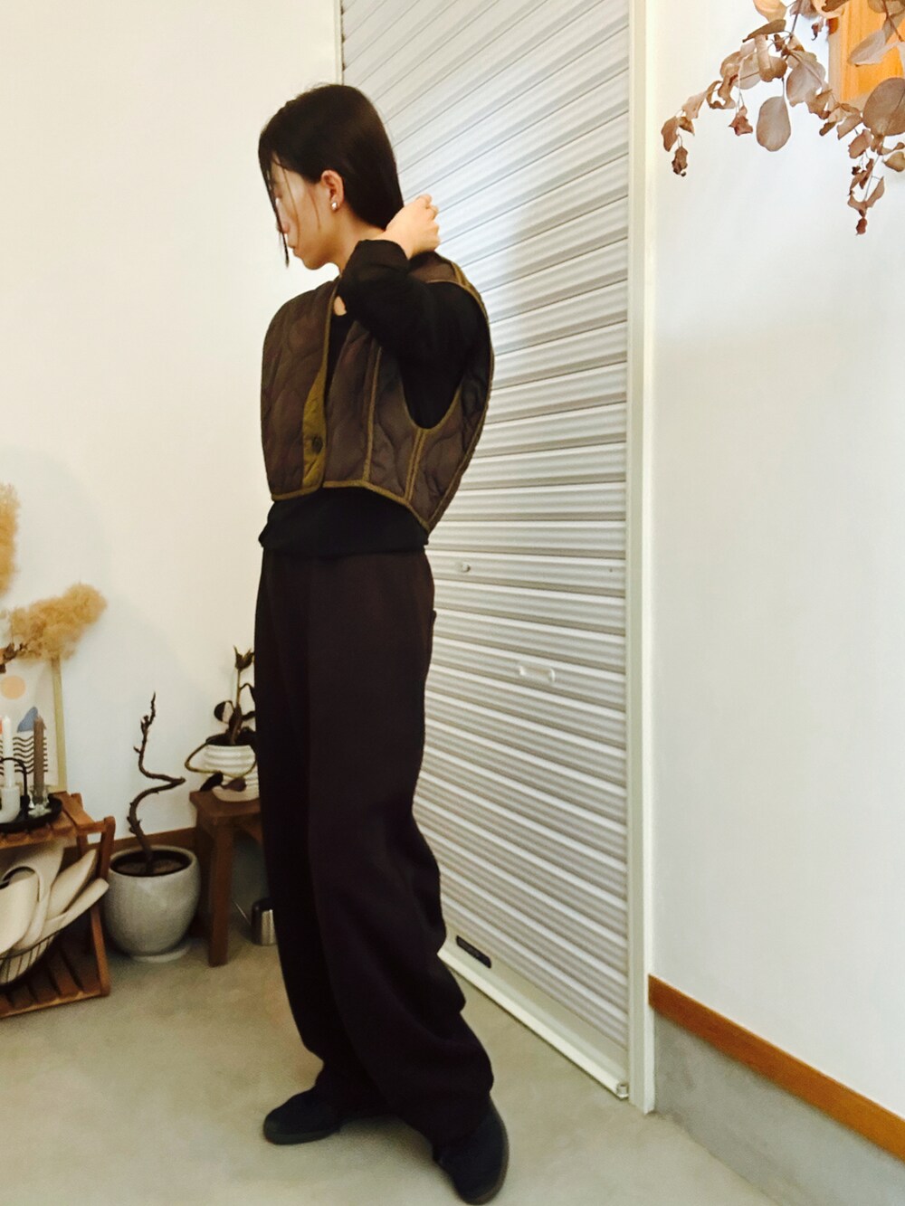 ブラウン系のベスト、ブラウン系のパンツ、ブラック系のスニーカーを着用したレディースの秋コーディネートの2枚目の写真