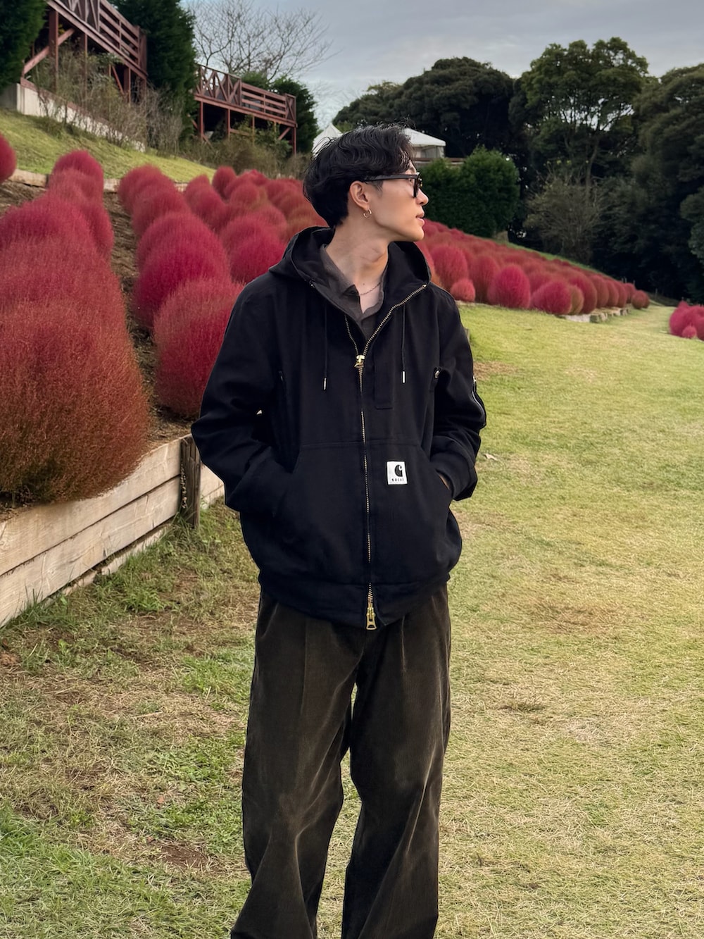 ブラック系のブルゾン、グリーン系のスラックス、ブラック系のスニーカーを着用したメンズの秋コーディネートの2枚目の写真