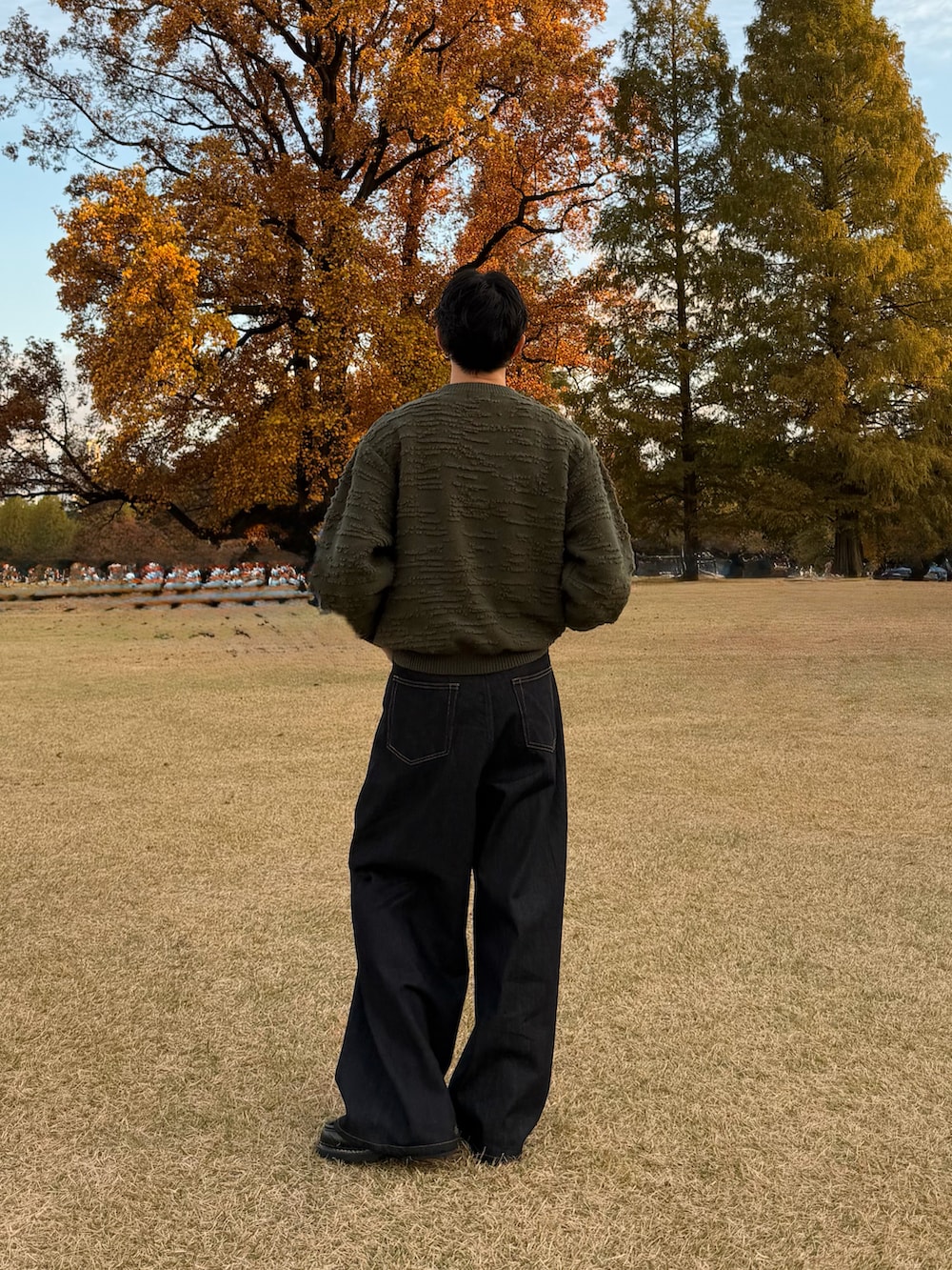 グリーン系のニット/セーター、ブルー系のデニムパンツ、ブラック系のドレスシューズを着用したメンズの冬コーディネートの3枚目の写真