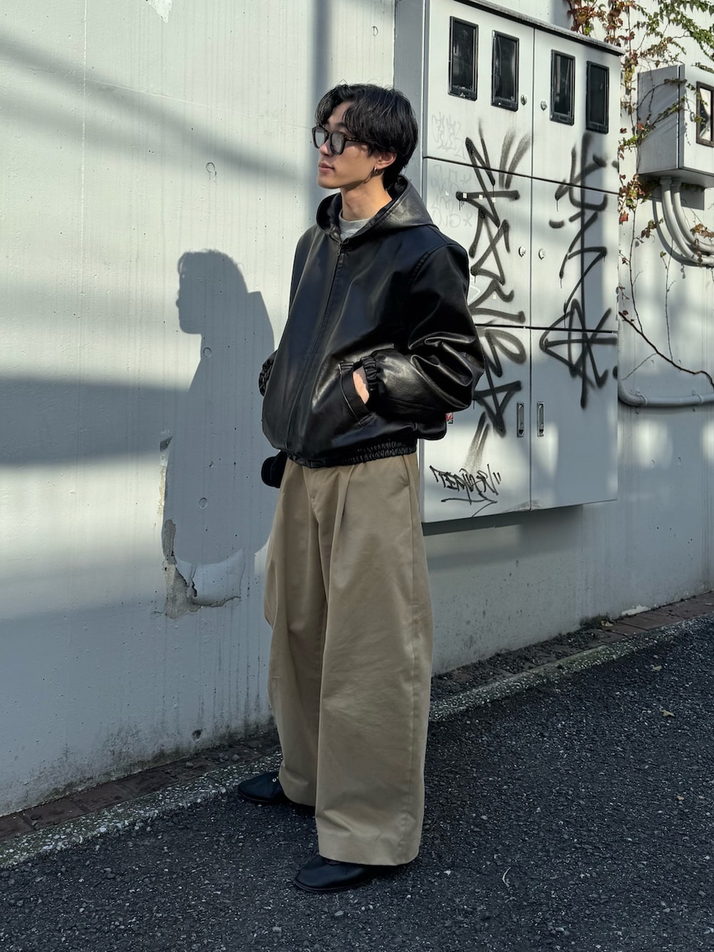 ブラック系のその他アウター、ベージュ系のその他パンツ、ブラック系のシューズを着用したメンズの冬コーディネートの2枚目の写真