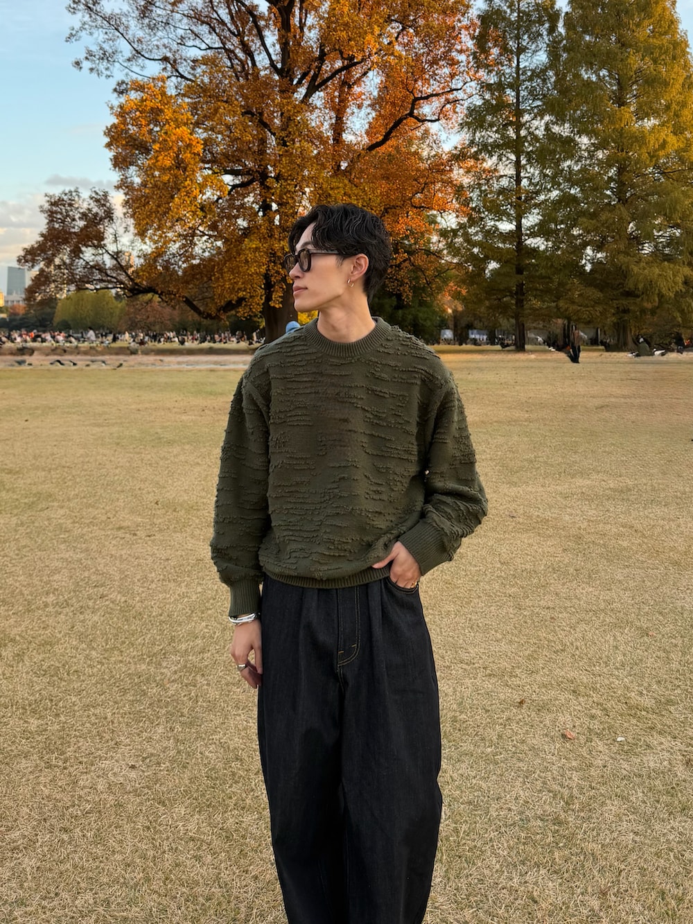 グリーン系のニット/セーター、ブルー系のデニムパンツ、ブラック系のドレスシューズを着用したメンズの冬コーディネートの2枚目の写真