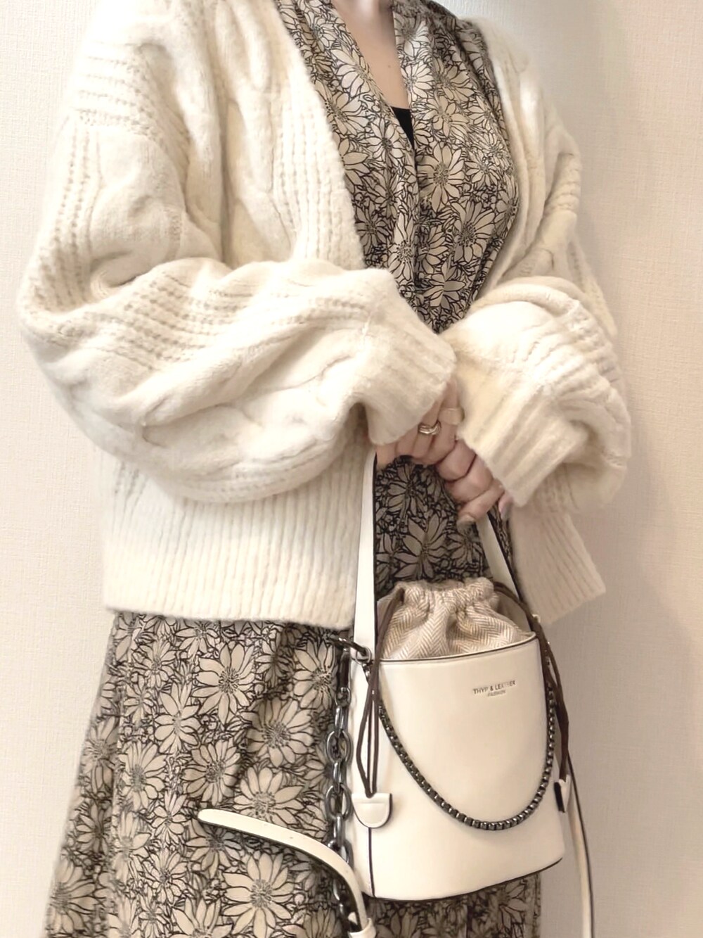 ホワイト系のショルダーバッグ、ベージュ系のワンピース、ホワイト系のニット/セーターを着用したレディースの春コーディネートの2枚目の写真