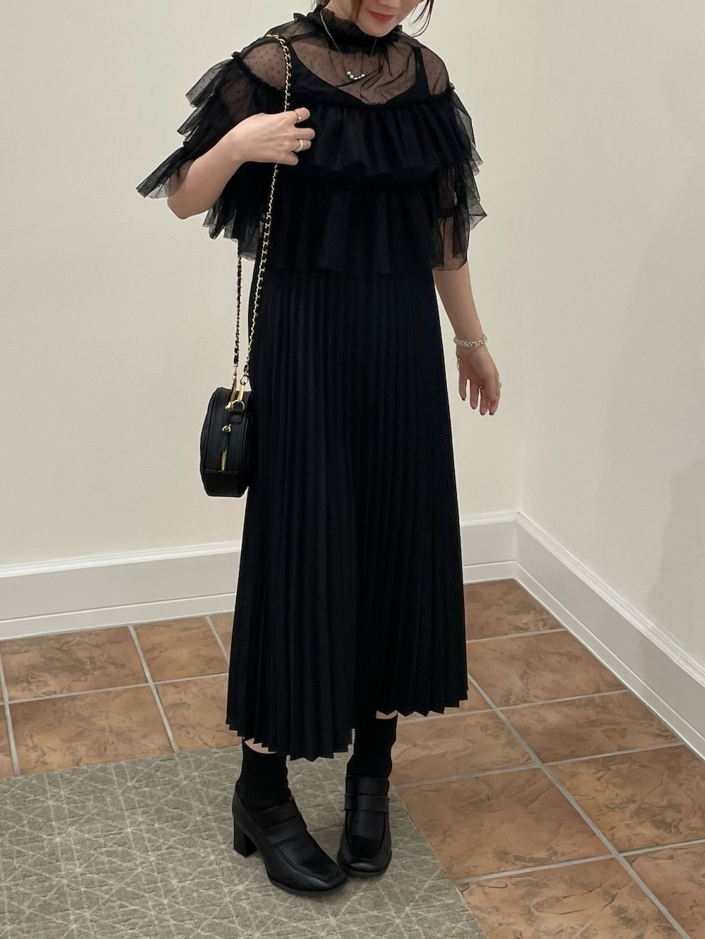 ブラック系のドレス、ブラック系のハンドバッグ、ブラック系のローファーを着用したレディースの秋コーディネートの5枚目の写真