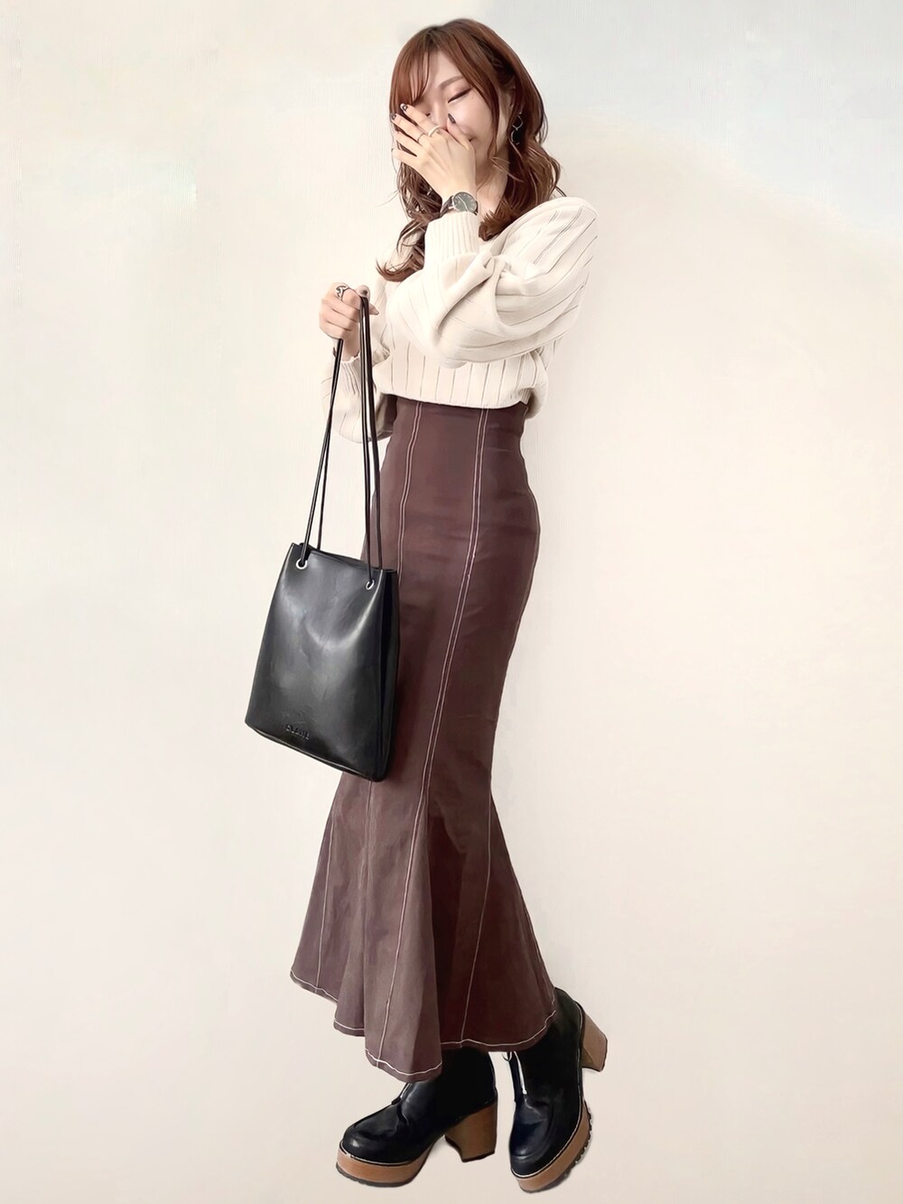 ホワイト系のニット/セーター、ブラウン系のスカート、ブラック系のブーツを着用したレディースの秋コーディネートの2枚目の写真