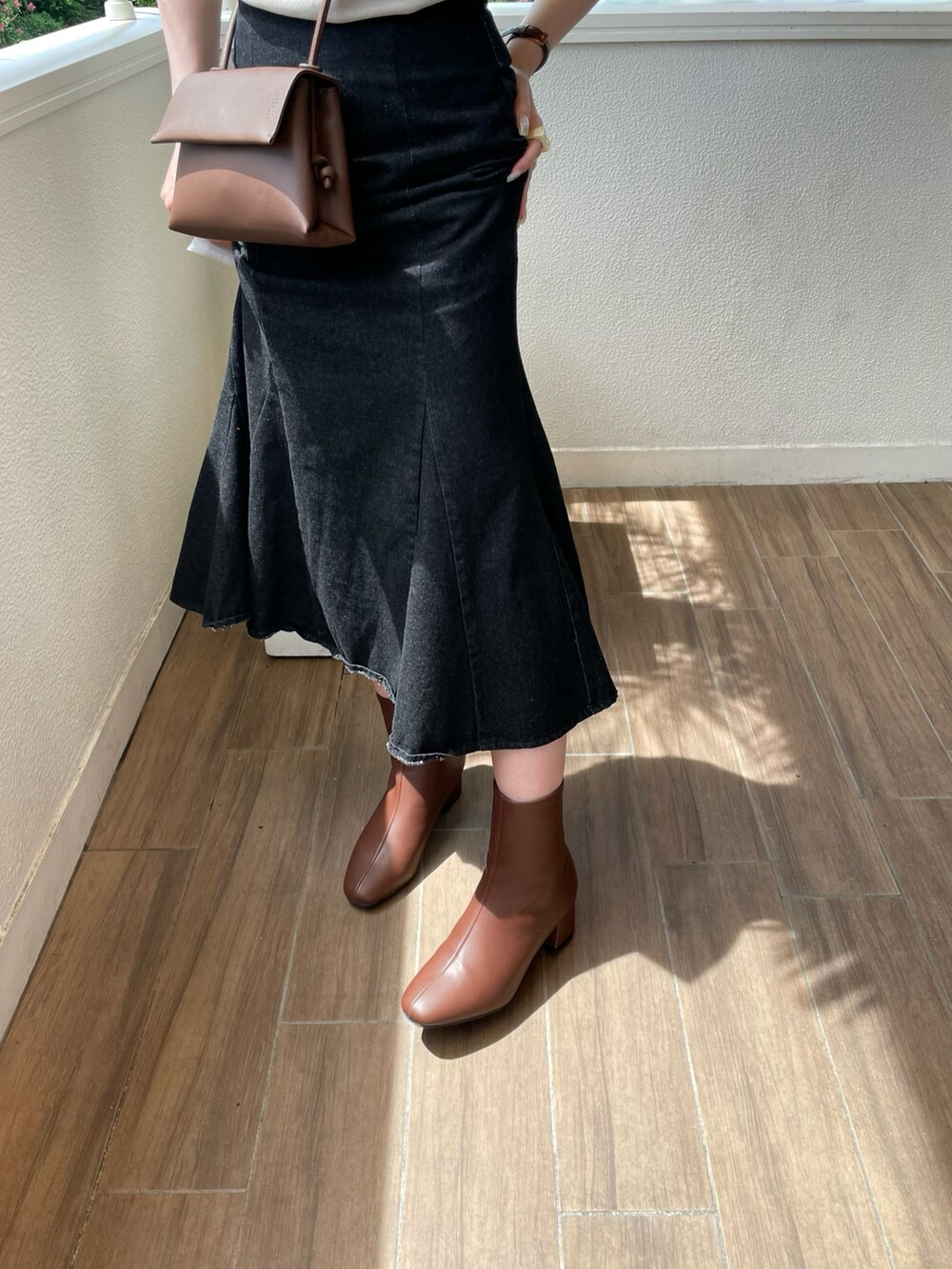 ブラウン系のブーツ、ブラック系のデニムスカートを着用したレディースの夏コーディネートの3枚目の写真