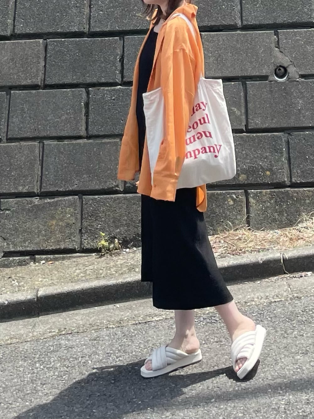 オレンジ系のシャツ/ブラウス、ホワイト系のトートバッグ、ホワイト系のサンダルを着用したレディースの夏コーディネートの3枚目の写真