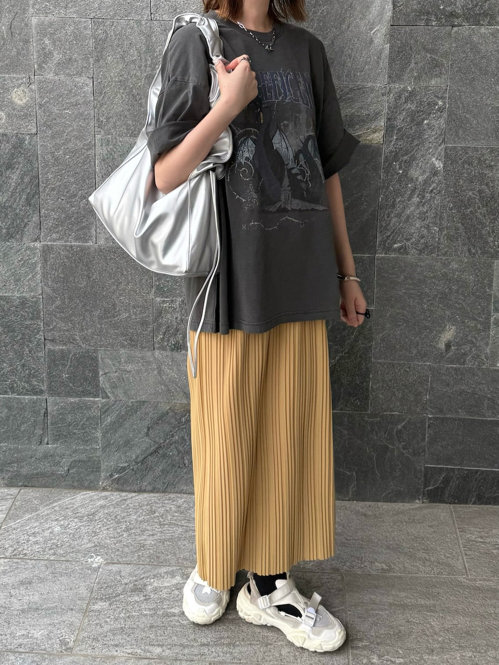 グレー系のTシャツ/カットソー、イエロー系のスカート、シルバー系のハンドバッグを着用したレディースの春コーディネートの3枚目の写真