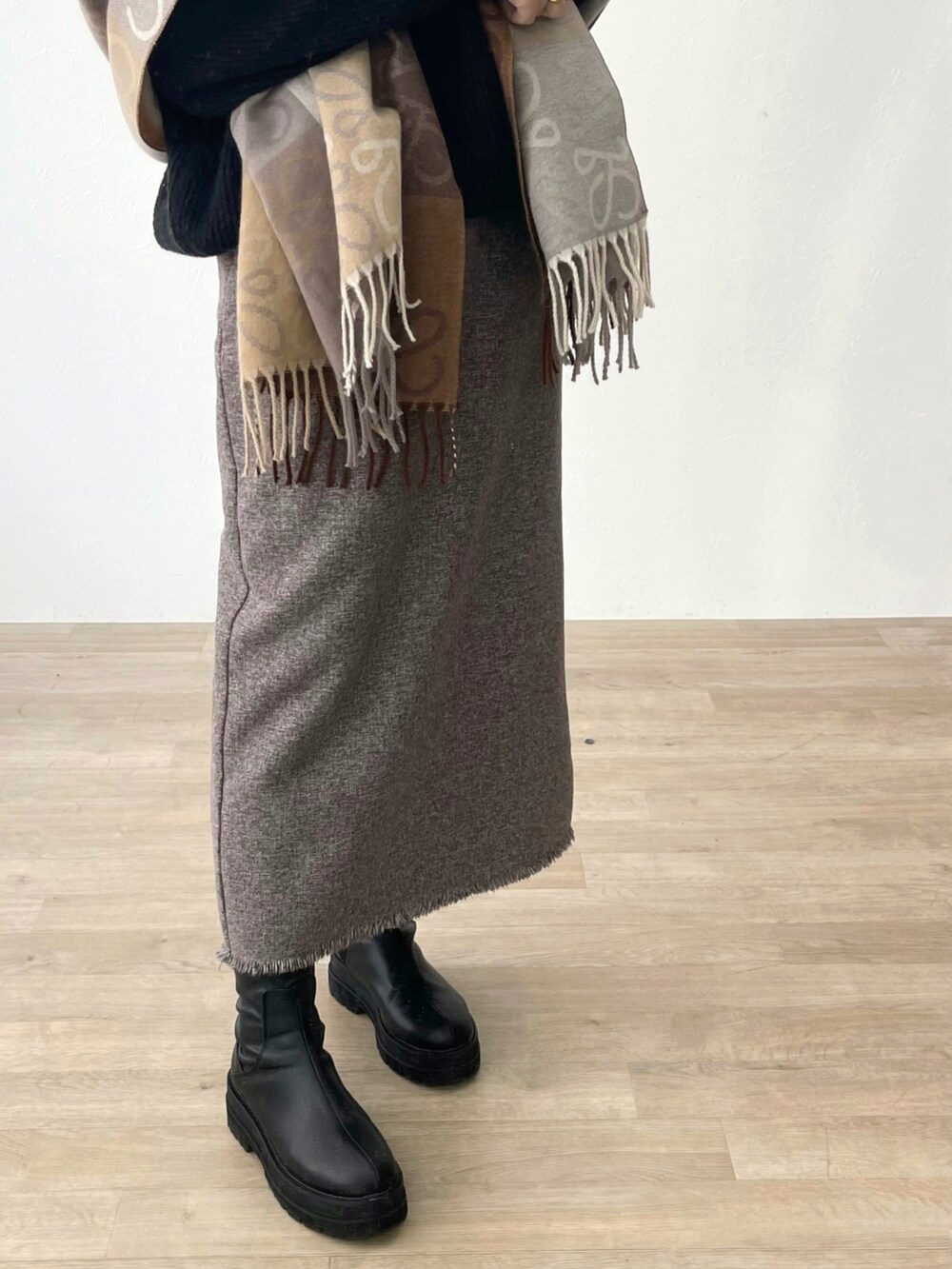 ブラウン系のスカート、ブラック系のブーツを着用したレディースの春コーディネートの3枚目の写真