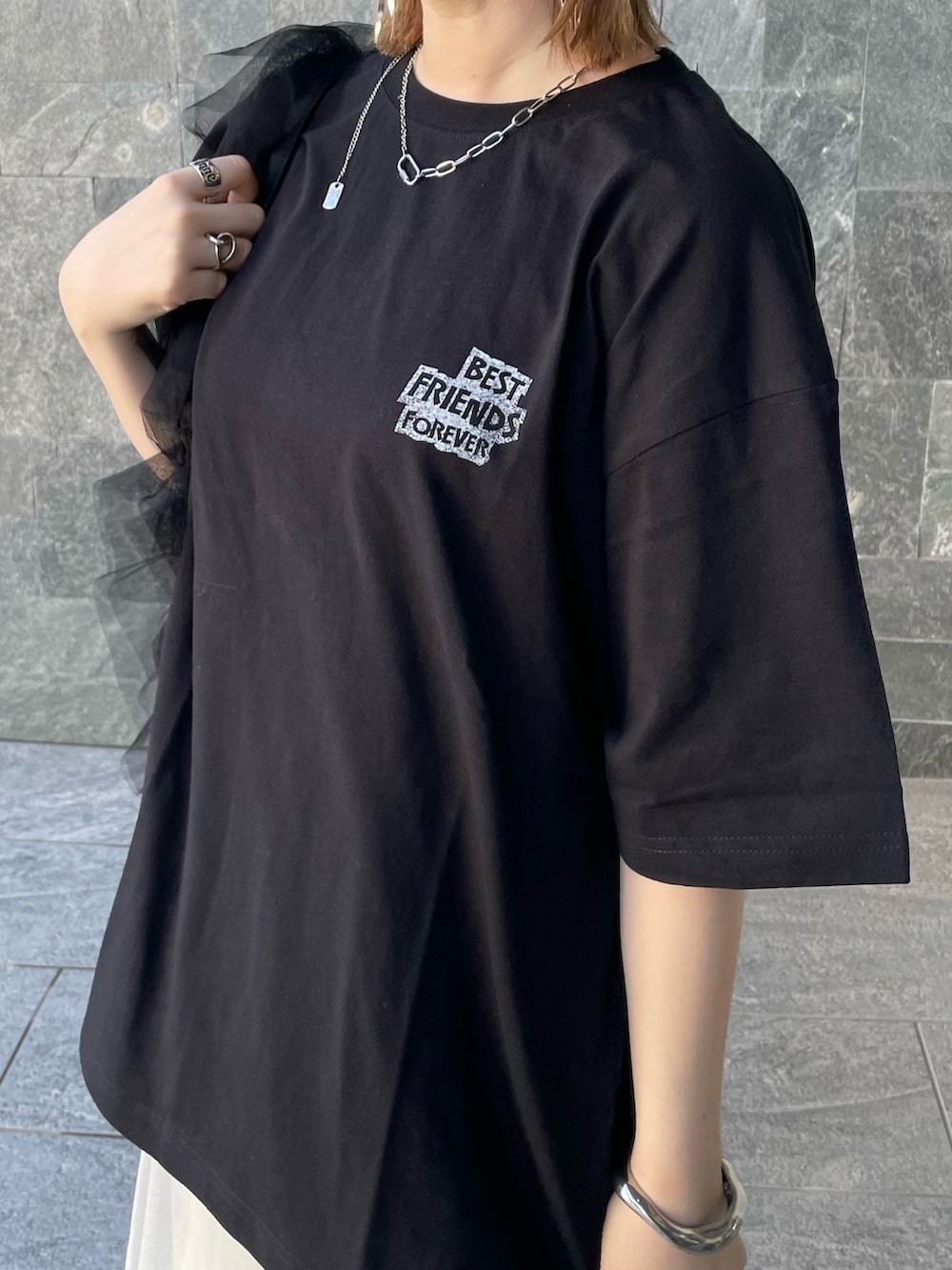 ブラック系のTシャツ/カットソー、ホワイト系のスカート、ブラック系のショルダーバッグを着用したレディースの春コーディネートの3枚目の写真