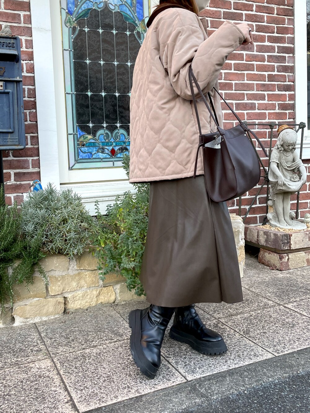 ベージュ系のブルゾン、ブラウン系のスカート、ブラック系のブーツを着用したレディースの秋コーディネートの2枚目の写真