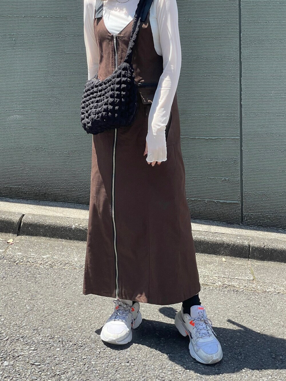 ブラウン系のジャンパースカート、ホワイト系のスニーカー、ブラック系のショルダーバッグを着用したレディースの春コーディネートの3枚目の写真