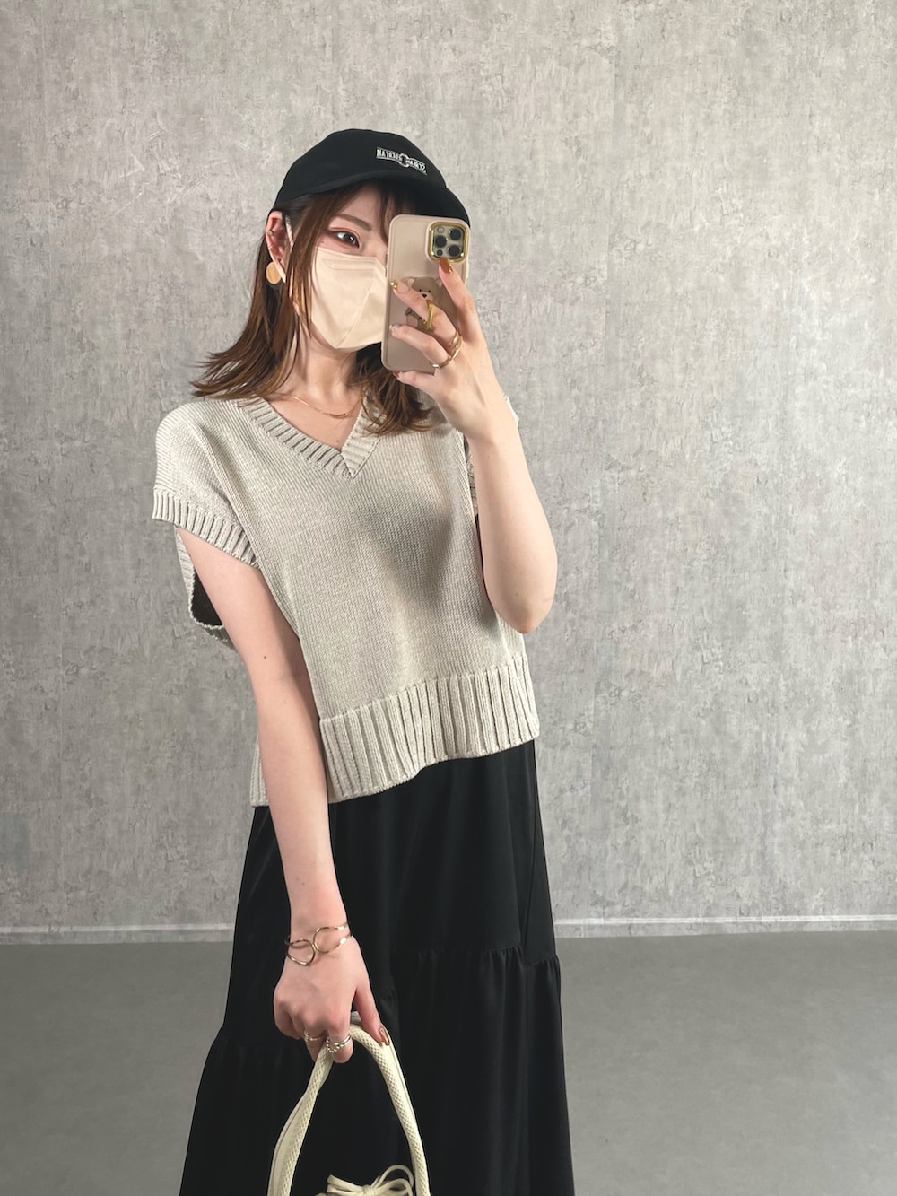 グレー系のベスト、ブラック系のワンピース、ホワイト系のハンドバッグを着用したレディースの夏コーディネートの2枚目の写真