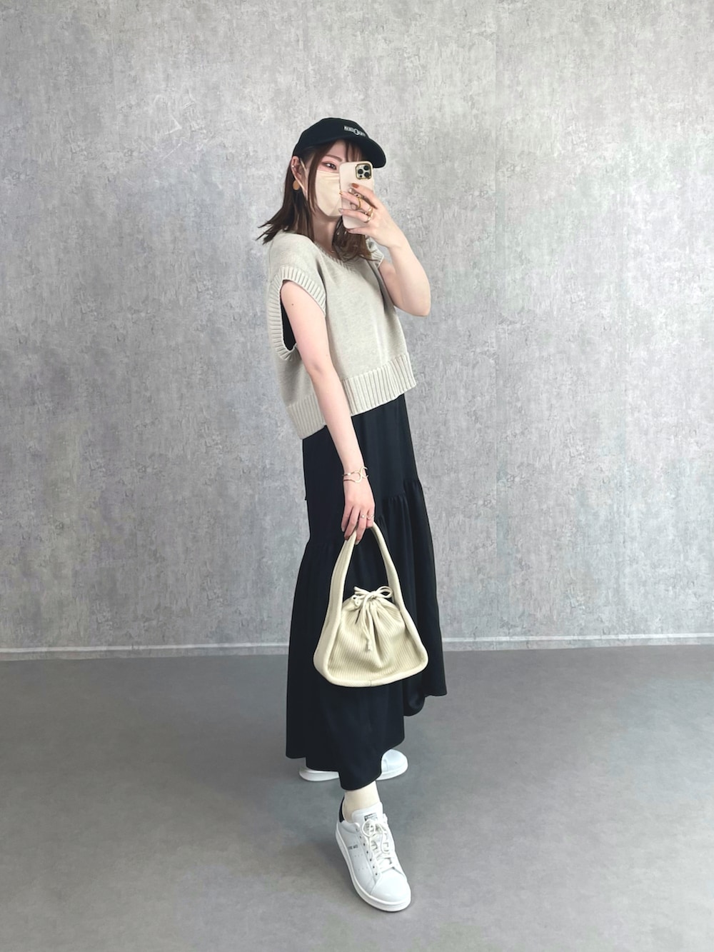 グレー系のベスト、ブラック系のワンピース、ホワイト系のハンドバッグを着用したレディースの夏コーディネートの3枚目の写真