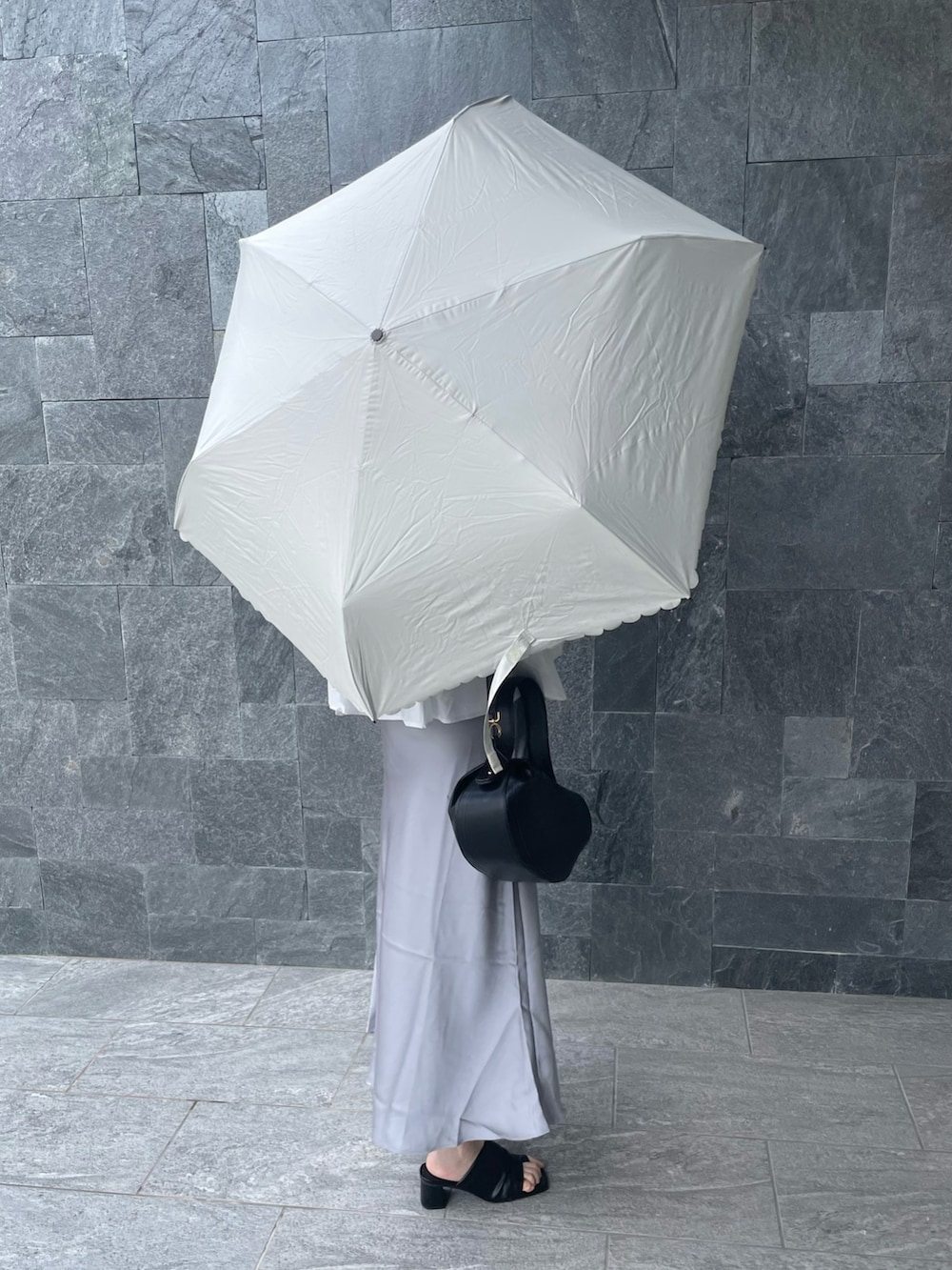 ホワイト系の折りたたみ傘を着用したレディースの夏コーディネートの2枚目の写真
