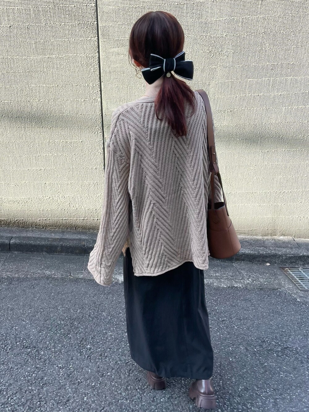 ベージュ系のニット/セーター、ブラウン系のハンドバッグを着用したレディースの冬コーディネートの3枚目の写真