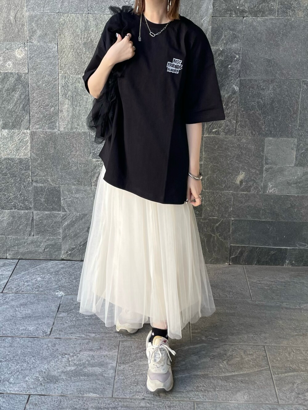 ブラック系のTシャツ/カットソー、ホワイト系のスカート、ブラック系のショルダーバッグを着用したレディースの春コーディネートの4枚目の写真