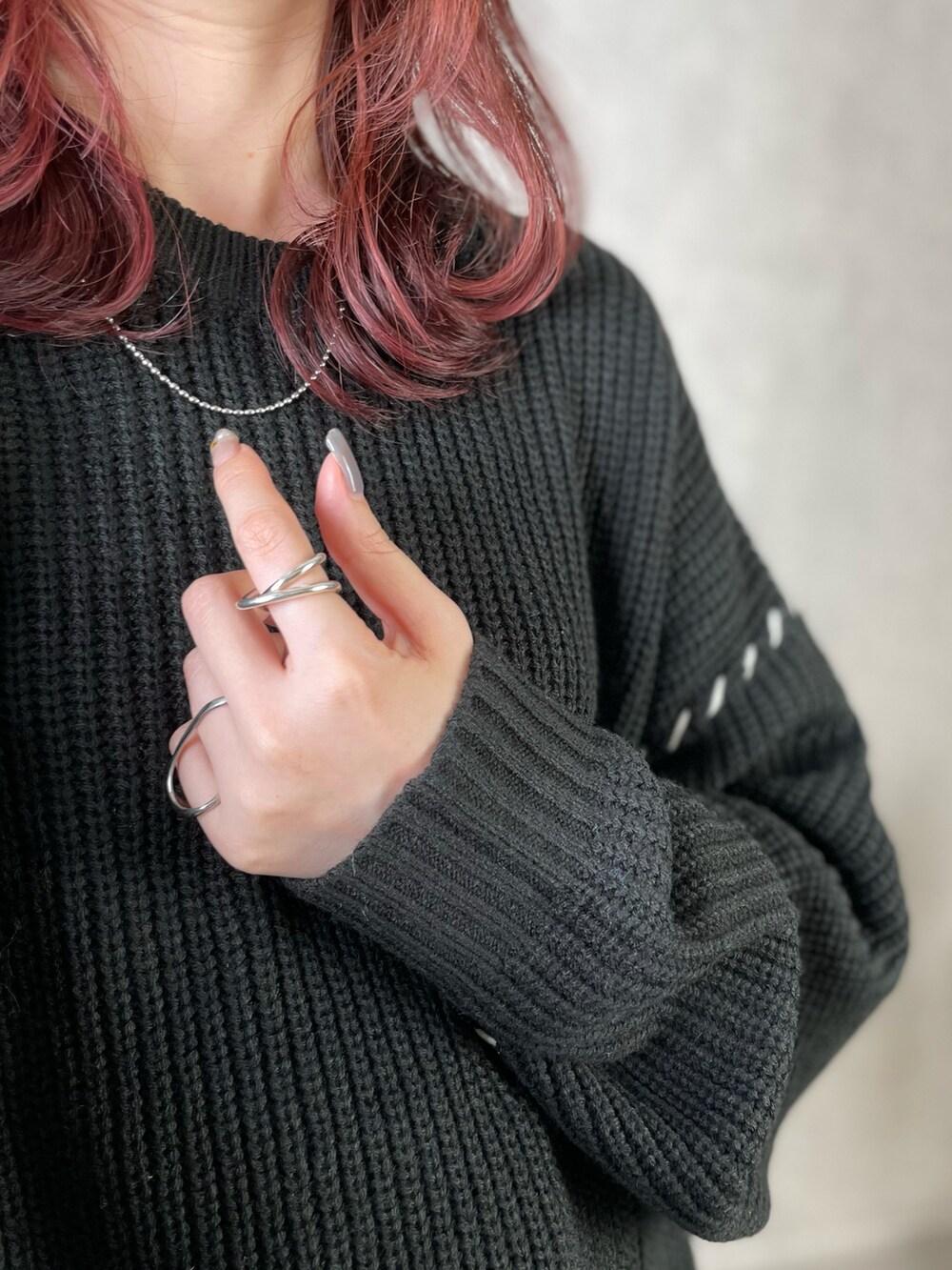 ブラック系のニット/セーター、ホワイト系のスカート、グレー系のバックパック/リュックを着用したレディースの秋コーディネートの2枚目の写真