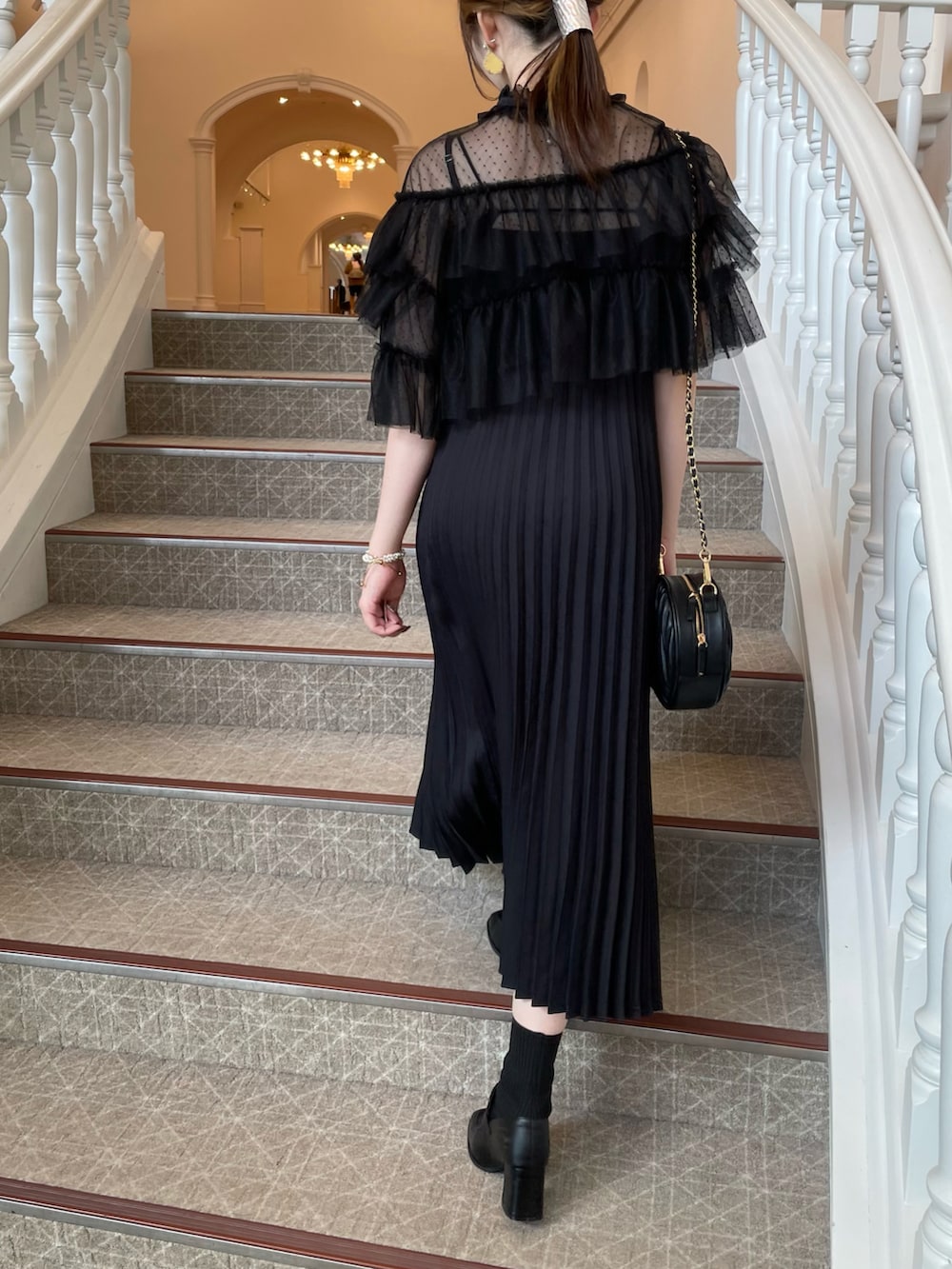 ブラック系のドレス、ブラック系のハンドバッグ、ブラック系のローファーを着用したレディースの秋コーディネートの2枚目の写真