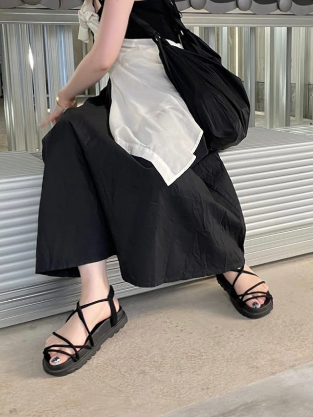 ブラック系のワンピース、ブラック系のサンダル、ブラック系のショルダーバッグを着用したレディースの夏コーディネートの2枚目の写真