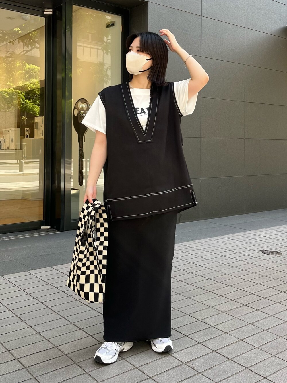 ブラック系のベスト、ブラック系のスカート、ホワイト系のTシャツ/カットソーを着用したレディースの春コーディネートの3枚目の写真