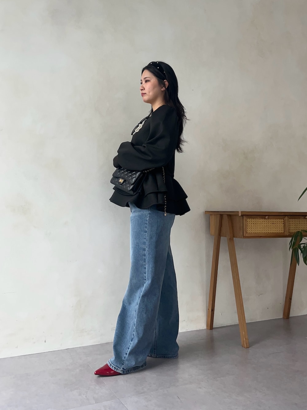 ブラック系のスウェット、ブルー系のデニムパンツ、レッド系のパンプスを着用したレディースの秋コーディネートの2枚目の写真