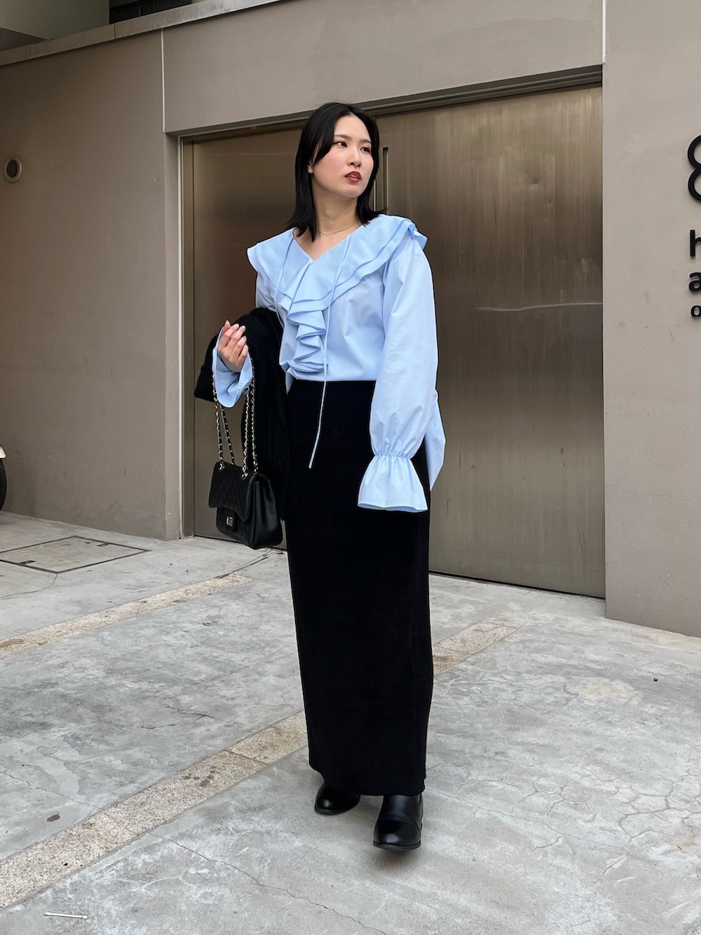 ブラック系のスカート、ブラック系のブーツ、ブラック系のショルダーバッグを着用したレディースの冬コーディネートの2枚目の写真