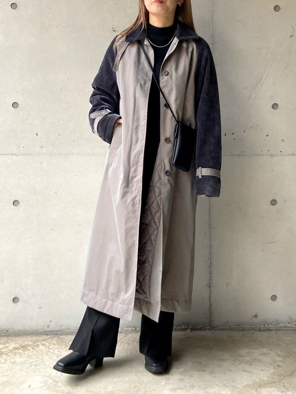 グレー系のステンカラーコート、ブラック系のショルダーバッグ、ブラック系のニット/セーターを着用したレディースの秋コーディネートの2枚目の写真